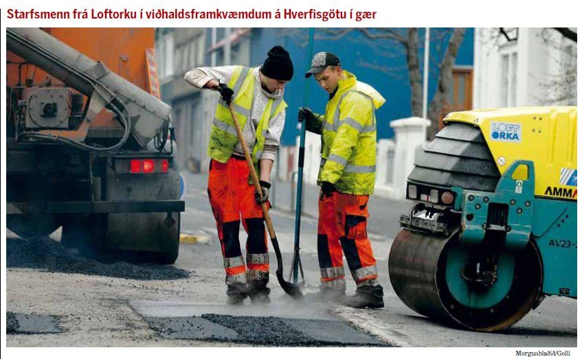 Tveir starfsmenn með skóflur við malbiksviðgerð í götu ásamt litlum valtara.